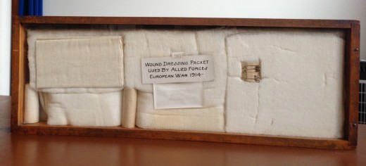 Shadowbox in our museum showing the Johnson & Johnson wound dressing packet for soldiers developed in 1914.